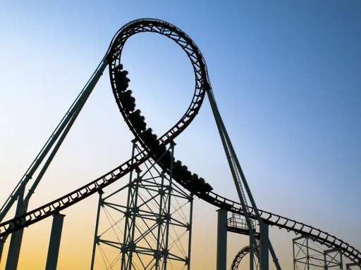 Roller coaster track with a loop against a clear sky at sunset.
