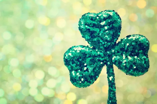 Glittery green shamrock against a blurred, sparkling background.