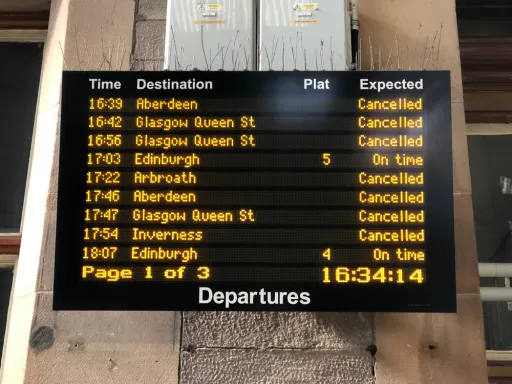 Digital departure board displays train times, destinations, platforms, and status updates.