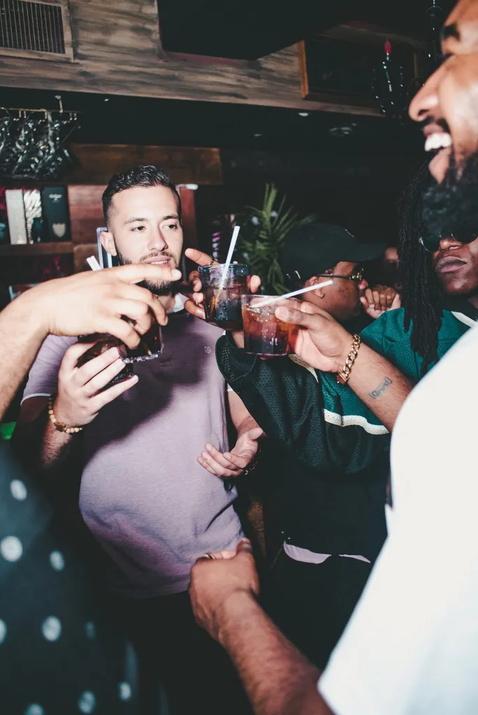 Group of friends raising glasses and enjoying drinks together in a lively bar, celebrating during a night out.