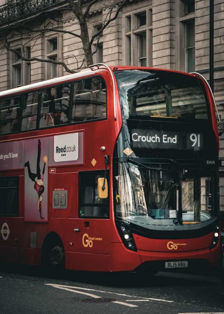  red double decker bus in front of a stone coloured building