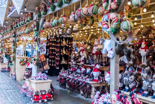 A festive market stall displaying various decorative items, including plush toys, ornaments, and wreaths
