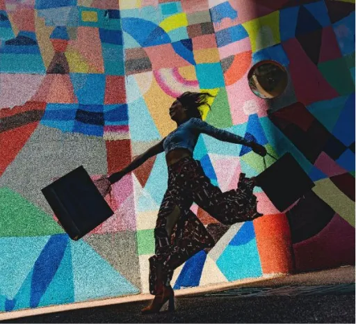 A person runs with shopping bags in front of a colourful abstract wall mural.