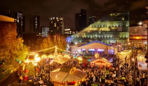 Bustling market scene at night with festive lights and a modern building in the background.