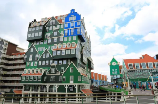 Colourful buildings with unique architectural designs, featuring green and blue facades, under a cloudy sky.